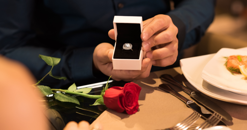 engagement ring in a box, red rose on table, proposal dinner